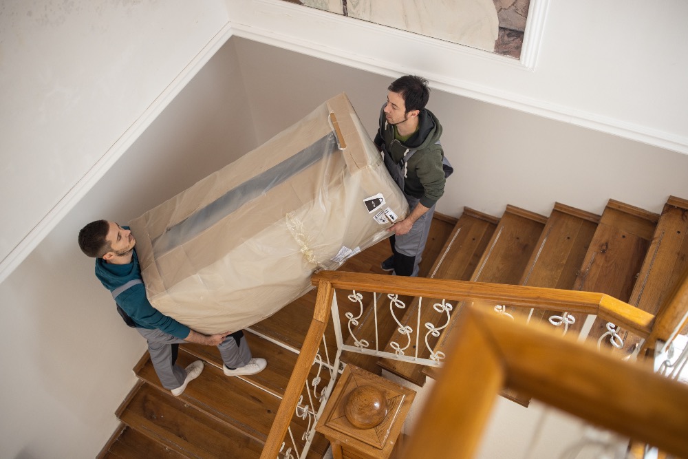 Two men carrying a large box up the stairs on moving day